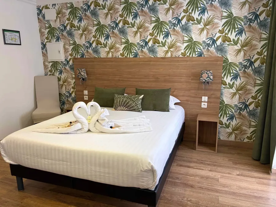 Elegant Junior Suite with tropical wallpaper, a cozy bed, and swan towels at Le Grand Hôtel Molière, Pézenas.