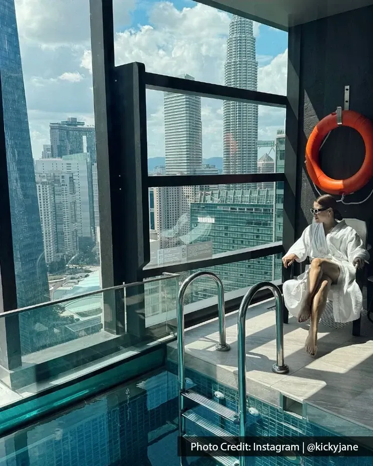 A woman relaxes in a private pool, enjoying a birthday staycation with a panoramic view of the Kuala Lumpur skyline.