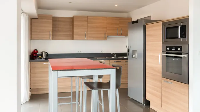 Modern kitchen with dining area and appliances in a hotel apartment at Appart’Hôtel Hévéa.