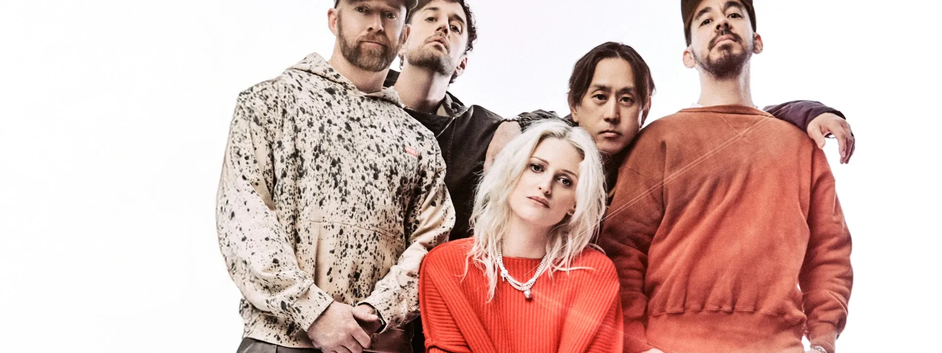 Five people standing close together, with a woman in the middle wearing a red sweater.