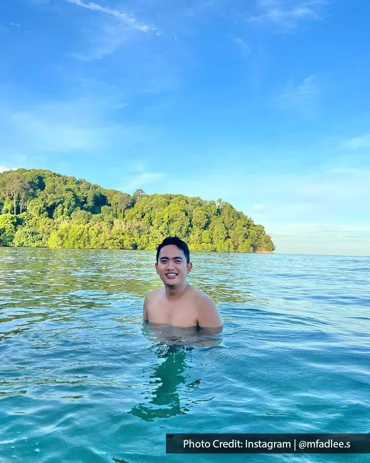 A man enjoying a refreshing swim at Pantai Tanjung Biru.