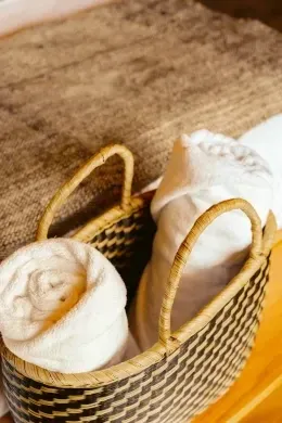 Wicker basket with rolled white towels and a robe on a wooden surface at Unika Hotels, the best places to stay in Bogota