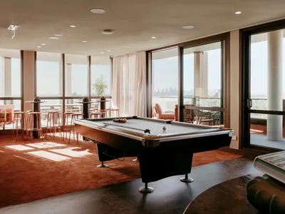 Billiards room with pool table, lounge chairs, and large windows at Caulfield Place.