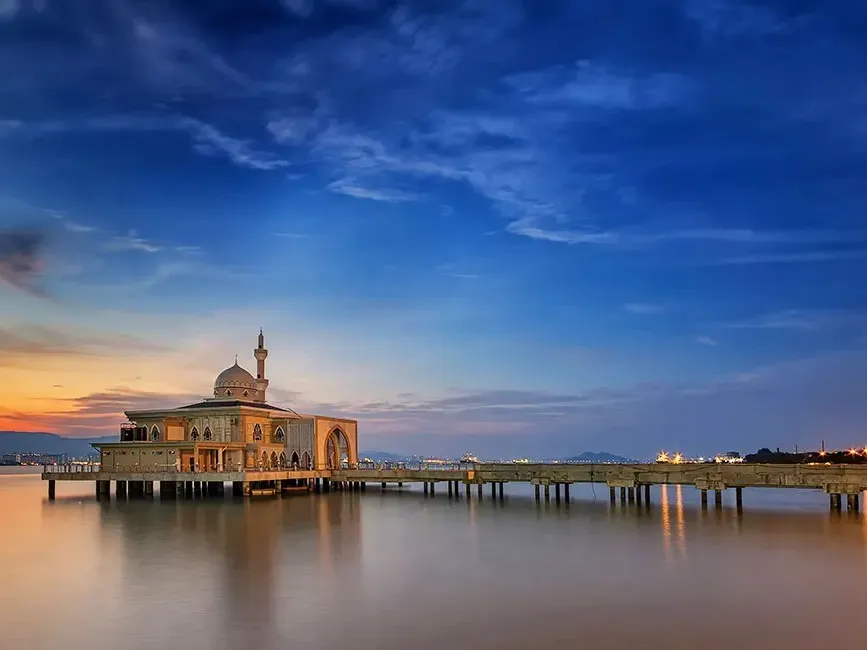 Sunset casts a warm glow over the Penang Floating Mosque, silhouetted against the vibrant sky - Lexis Suites Penang