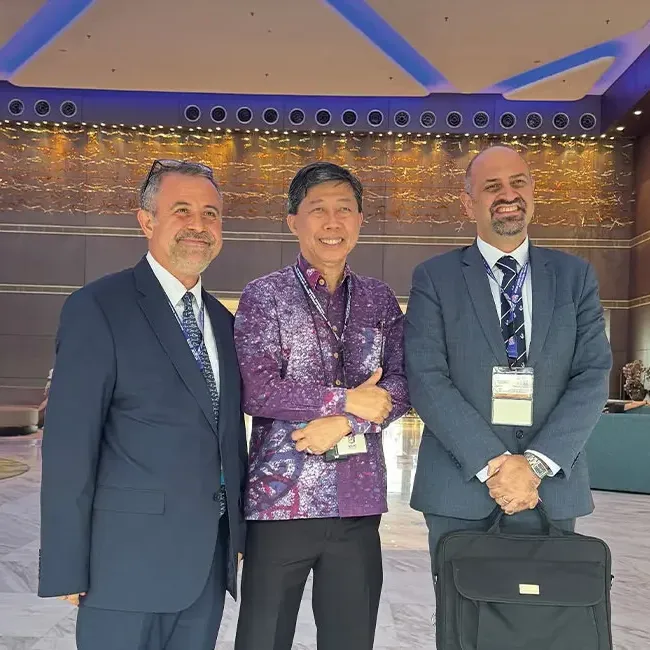 Three men posing for a photo together in a hotel lobby - Lexis Hotel Group
