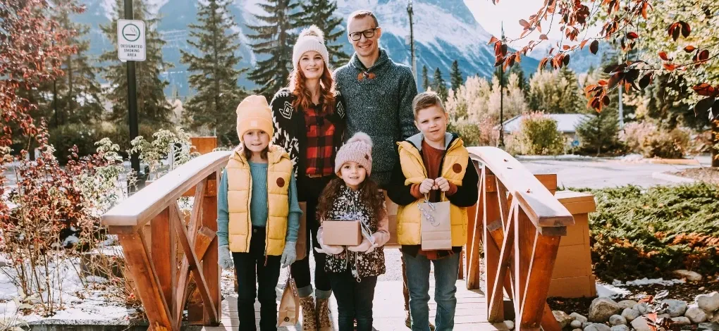 A family of five pose on a bridge leading into downtown Canmore on a fall day.