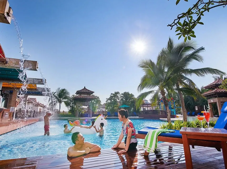 People relaxing beside outdoor swimming pool.