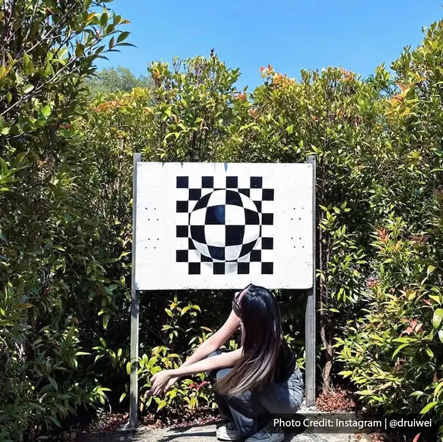 Visitor crouching in front of optical illusion board at PD Maze – Lexis Hibiscus Port Dickson