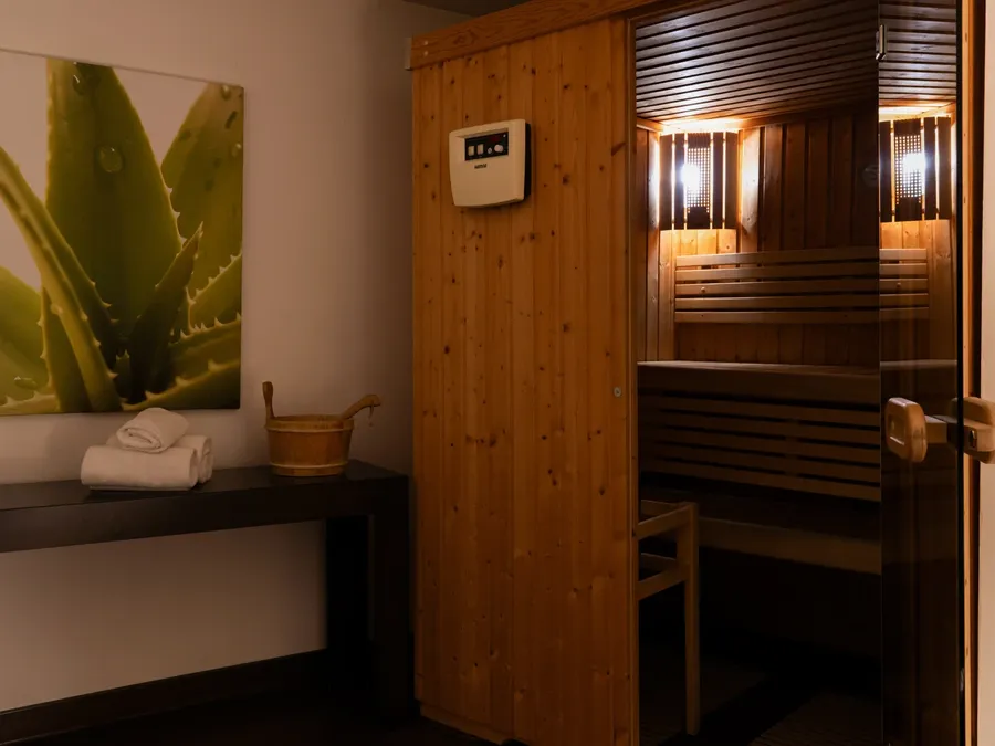 Sauna room with wooden benches and towels on a shelf at Appart’Hôtel Hévéa.
