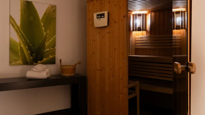 Sauna room with wooden benches and towels on a shelf at Appart’Hôtel Hévéa.