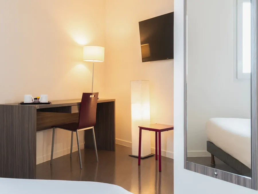A neat Standard Studio with a desk and mirror at Appart’Hôtel Hévéa in Valence.