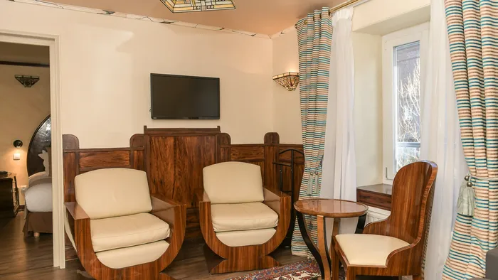 Chambre élégante avec trois fauteuils et une table basse chez Hôtel Villa Aultia.