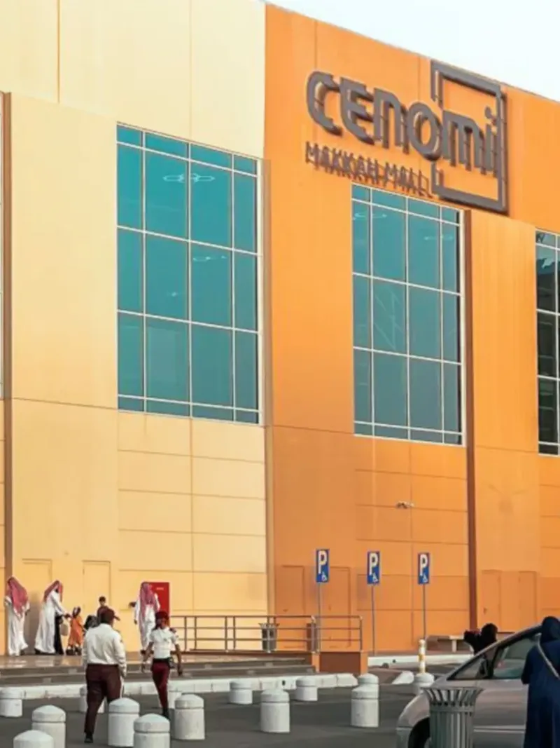 Vue extérieure du centre commercial Cenomi Makkah, avec des clients et des voitures garées près de l'hôtel Saja by Warwick Makkah