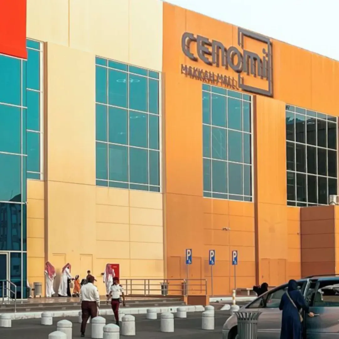 Exterior view of the Cenomi Makkah Mall building with shoppers and parked cars near Saja by Warwick Makkah
