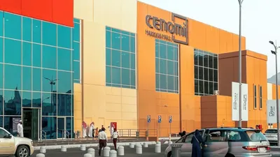 Exterior view of the Cenomi Makkah Mall building with shoppers and parked cars near Saja by Warwick Makkah