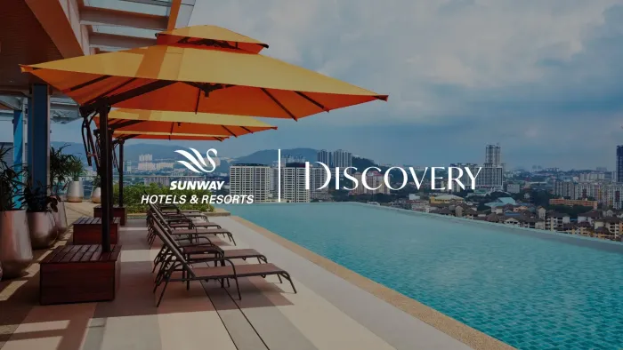 Discovery poster with an outdoor pool, lounge chairs, and large orange umbrellas at Sunway Velocity Hotel