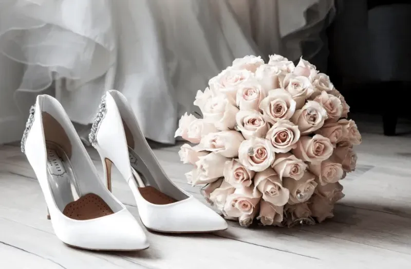 White wedding shoes and a bouquet of roses on wooden floor at Naviti Warwick Al Khobar