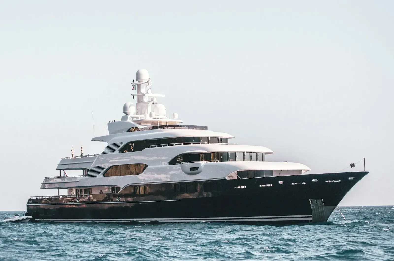 A dark-hulled motor yacht resting at anchor offshore