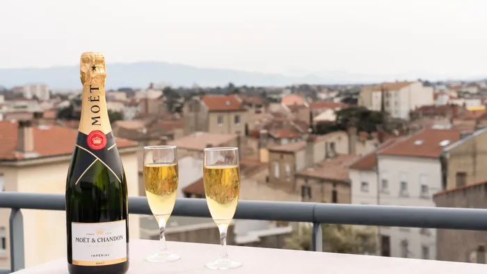 Bottle and two glasses of Moet & Chandon champagne on balcony overlooking cityscape.