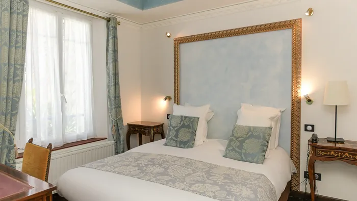Chambre élégante avec lit, lampes, et bureau au Hôtel Villa Aultia.