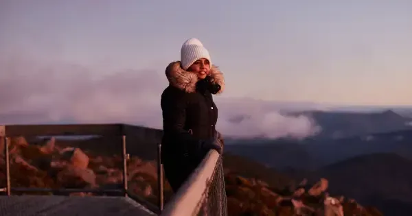  A woman stands at the Mt. Wellington lookout wearing warm winter clothing.