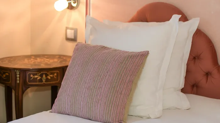 Lit avec oreillers et table de chevet élégante à l'Hôtel Villa Aultia.