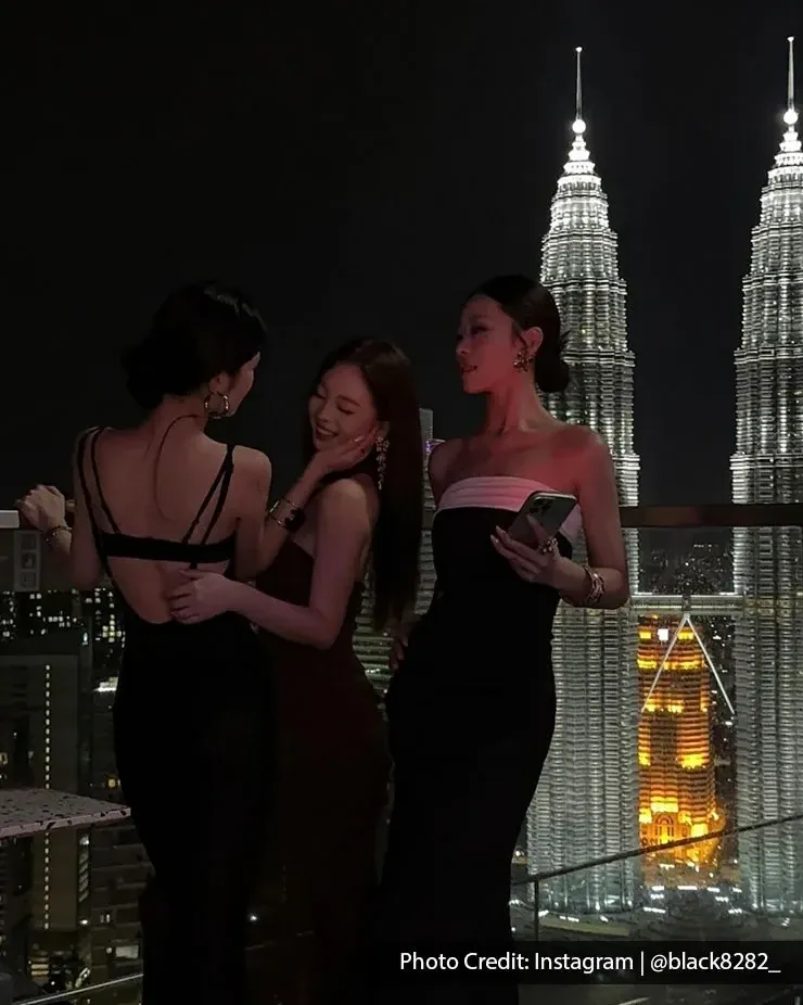 Friends posing at night with the iconic Petronas Twin Towers in the background.