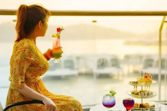 A woman enjoying beautiful sunset and beverage at Lexis Hibiscus