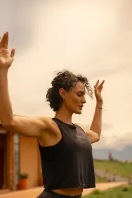 Woman stretching with raised arms outdoors beneath a warm sunset sky near Unika Hotels, an elite hotel in Bogota, Colombia