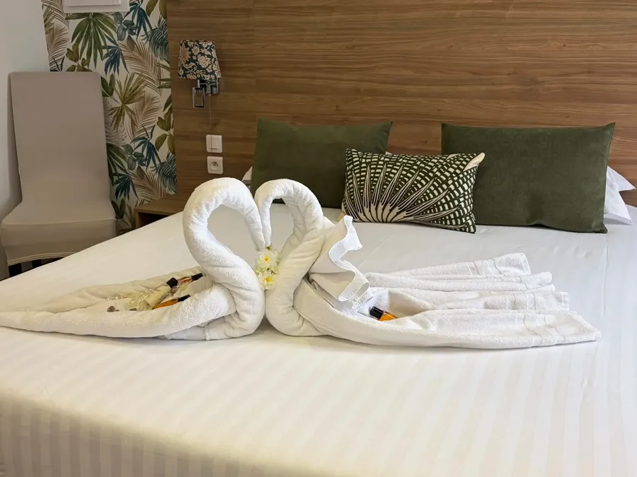 Cozy Junior Suite bed with swan-shaped towels at Le Grand Hôtel Molière in Pézenas.
