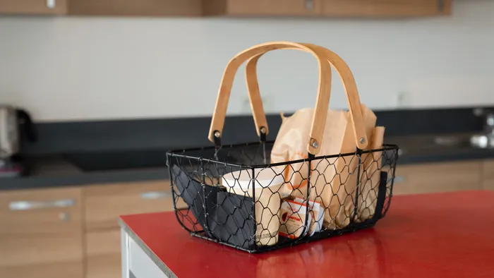 A basket with food on a red counter in a kitchen at Appart’Hôtel Hévéa.
