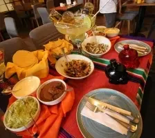 Vibrant Mexican feast of nachos with guacamole and dipping bowls beside a large iced goblet at Unika Hotels