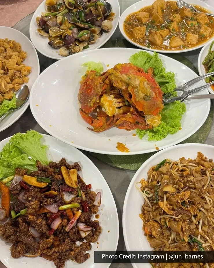 Table spread with crab, noodles and stir-fried dishes.