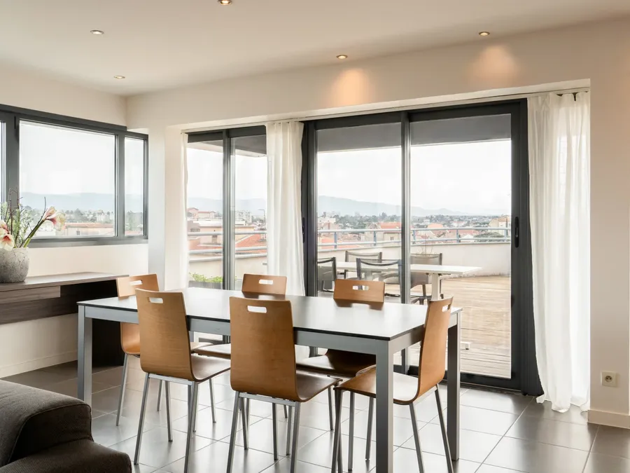 Modern two-bedroom apartment with dining area and balcony view at Appart’Hôtel Hévéa in Valence.