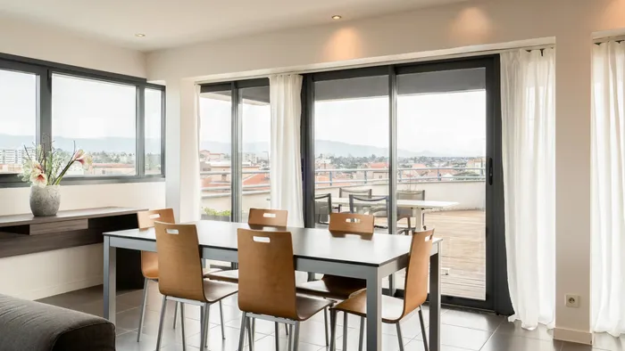 Dining table with chairs and city view from balcony at Appart’Hôtel Hévéa