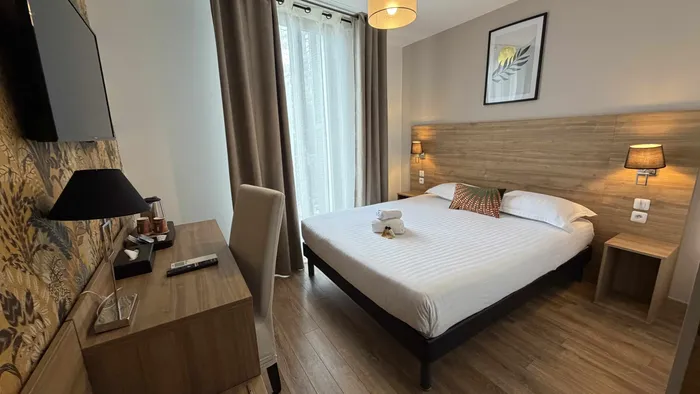 Chambre élégante avec lit double, bureau et télévision au Grand Hôtel Molière.