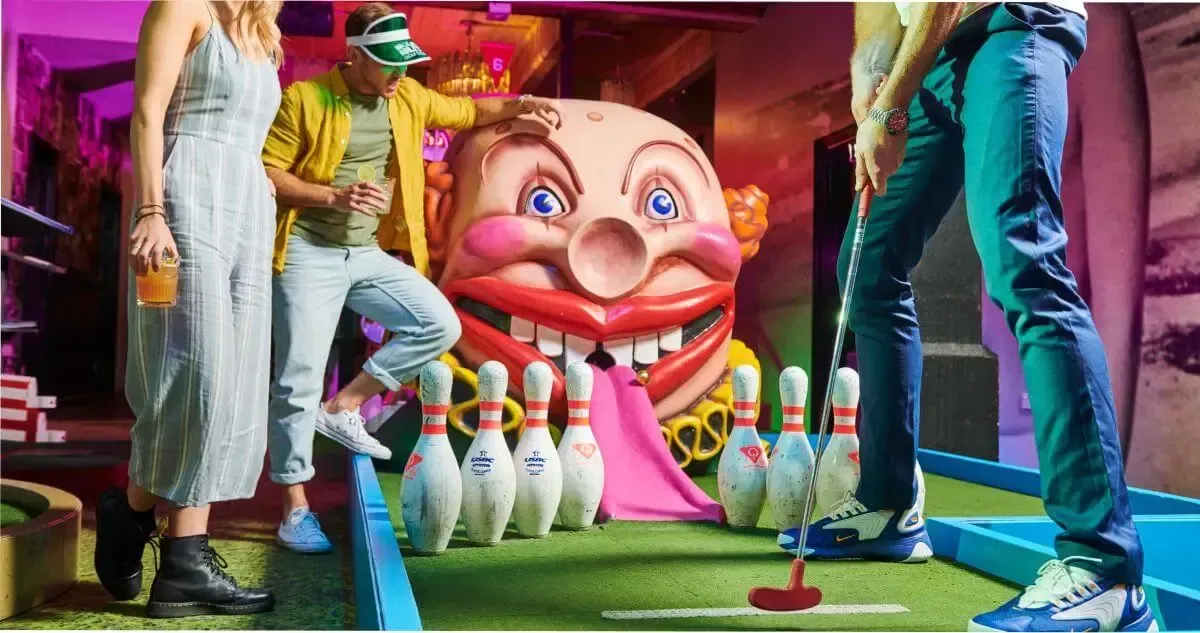 A group of people drinking and playing mini golf at Holey Moley in Adelaide