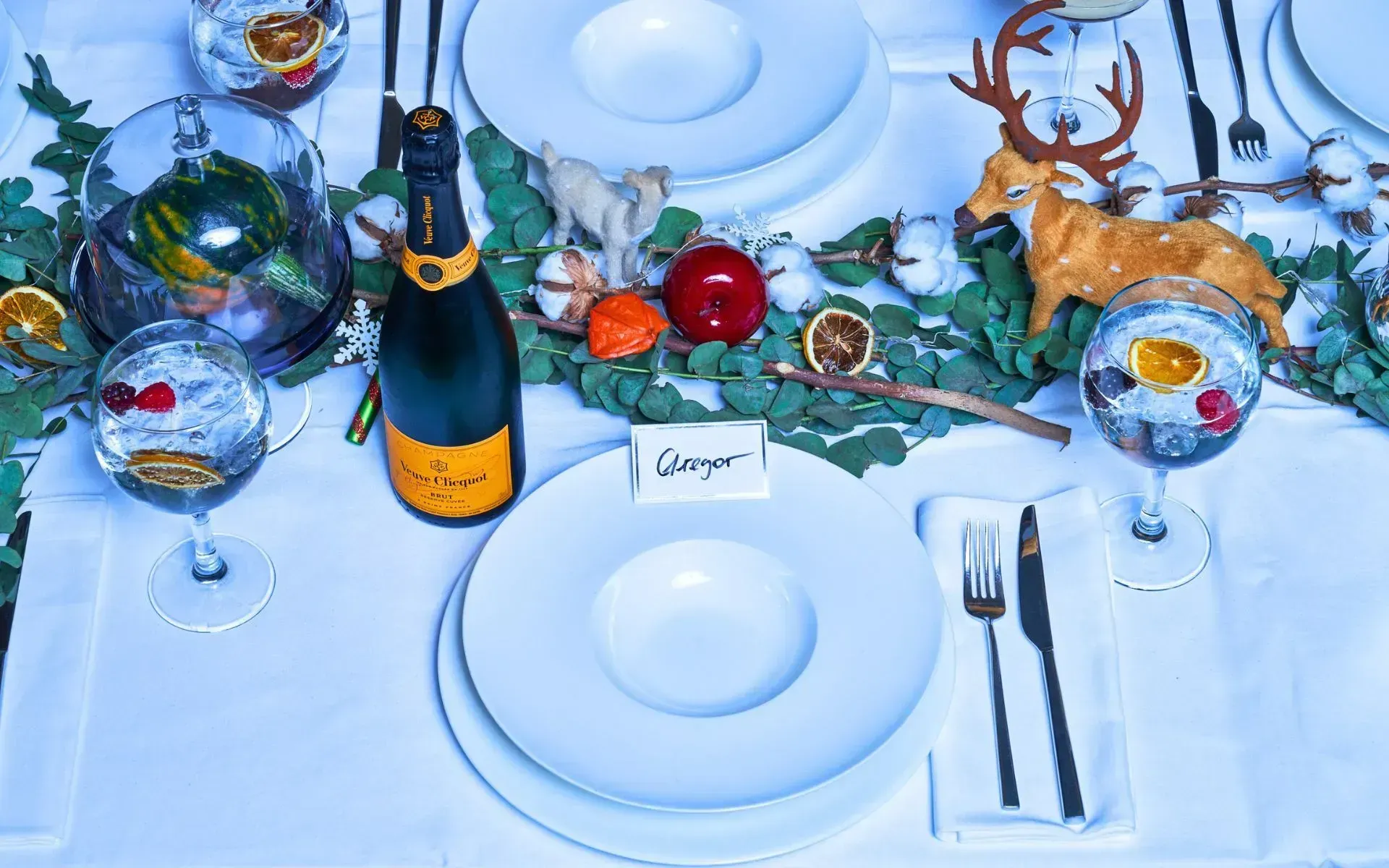 A festive table setting featuring a bottle of champagne alongside a decorative deer figurine at Flemings Hotels