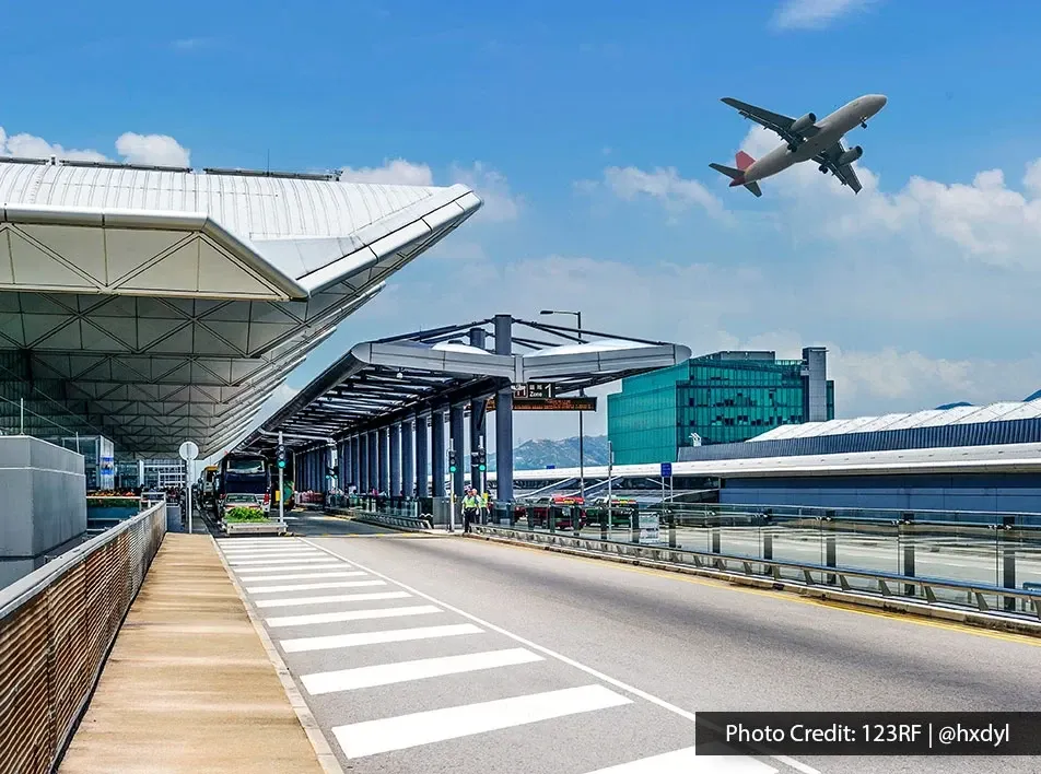 Airport departure terminal building with commercial plane taking off in blue sky