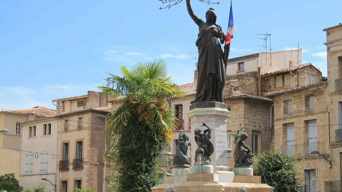 Statue de la Liberté à Pézenas, devant des bâtiments anciens, près du Grand Hôtel Molière