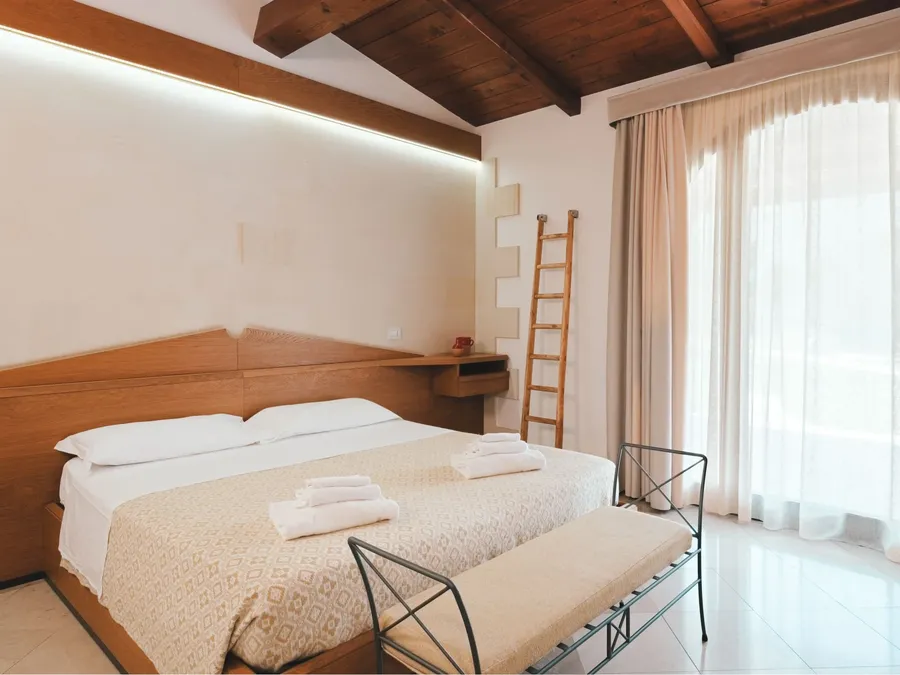 Chambre familiale spacieuse avec un grand lit, des oreillers et des serviettes à l'hôtel Masseria Stali à Caprarica di Lecce.