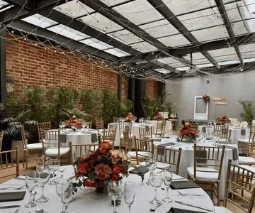 Banquet tables with floral centerpieces under fairy lights in a glass roof courtyard venue at Hotel B3 Virrey