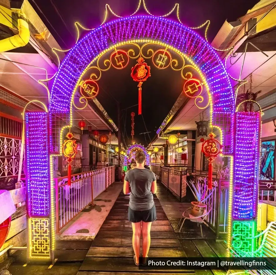 Woman walking under a brightly lit arch at Clan Jetty.