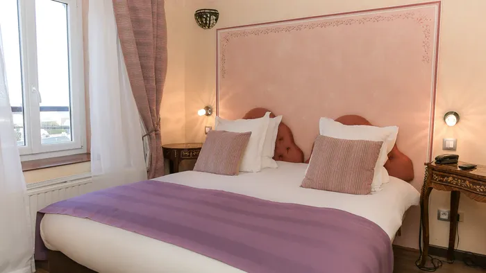Chambre confortable avec lit, oreillers et couverture violette à l'Hôtel Villa Aultia.