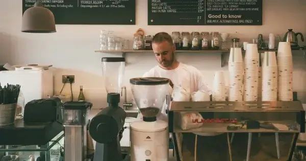 Man in white shirt brewing coffee in front of counter