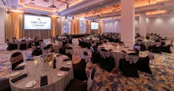 A banquet room set with round tables and screens for a sporting club presentation dinner