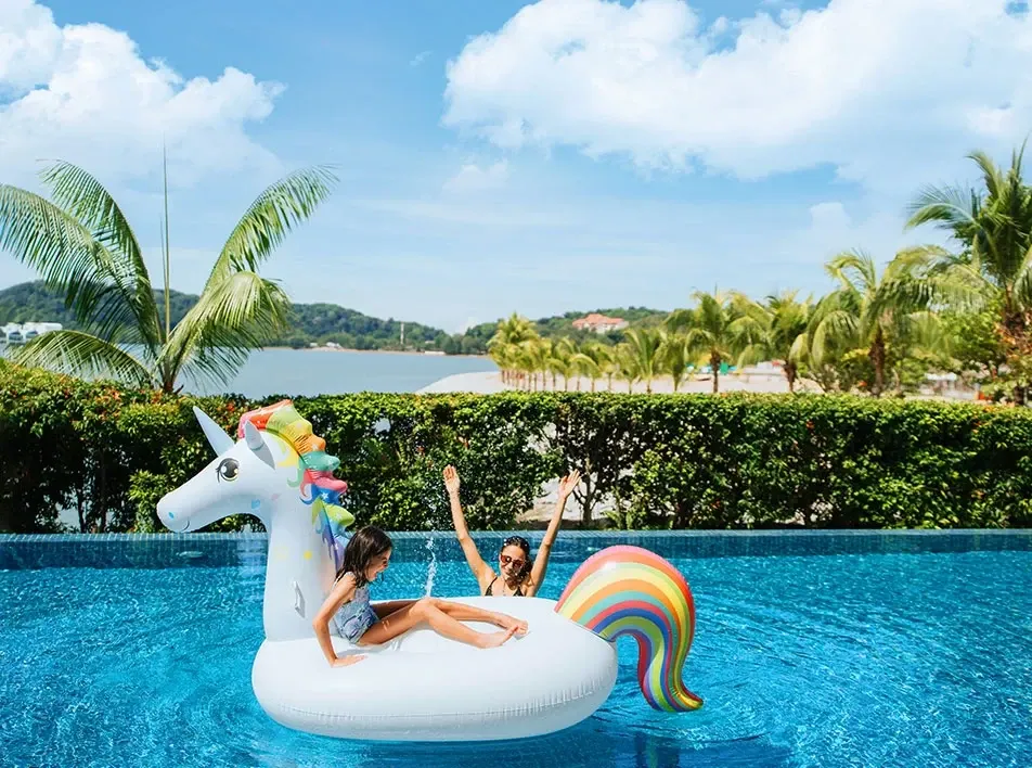 Guests enjoying a resort swimming pool with a unicorn float at Lexiis Hibiscus Port Dickson