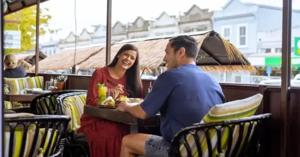 A couple laughing as they eat on the balcony at Blue Breeze Inn in Ponsonby, Auckland