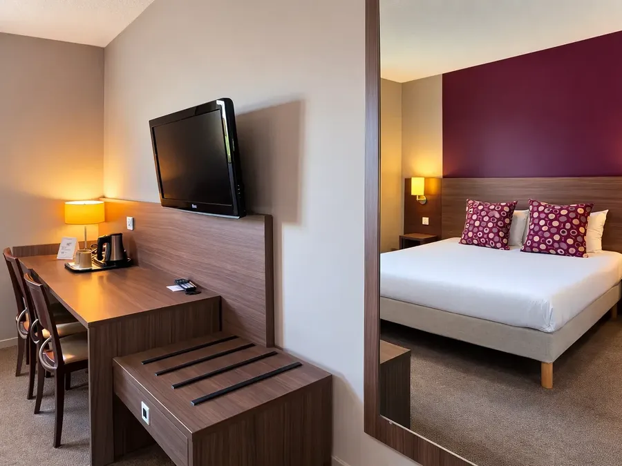 Chambre double élégante avec lit, bureau et télévision au Hotel Les Bruyères à Castets.