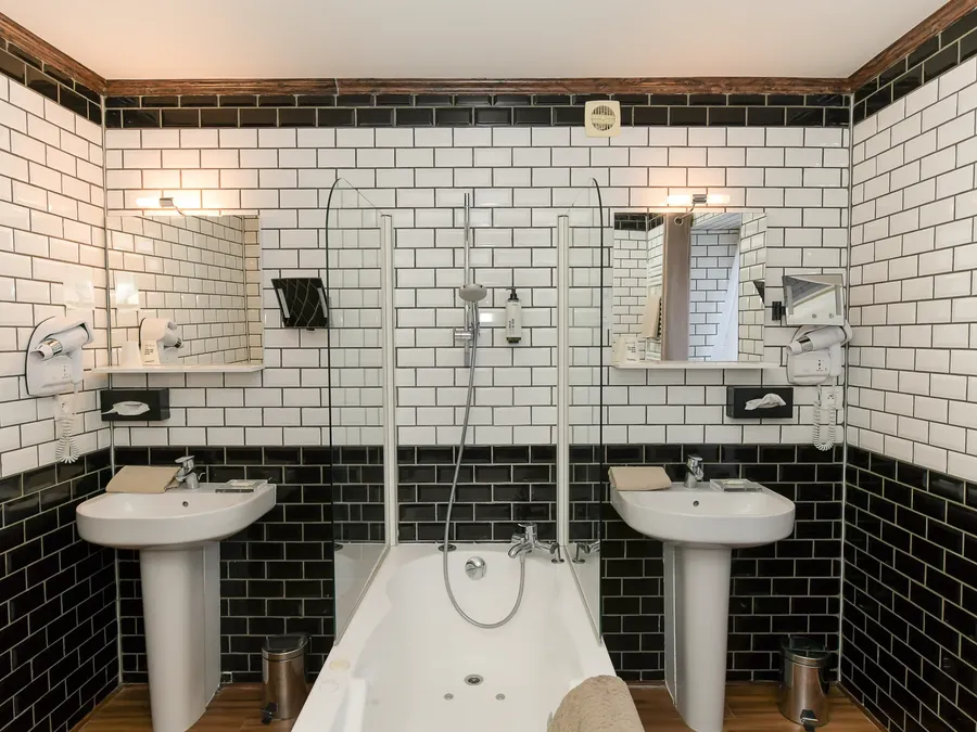 Salle de bain élégante avec deux lavabos et une baignoire au Hôtel Villa Aultia à Ault.
